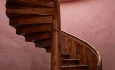 An elegant photo of a spiral staircase in a South American cultural institute, showcasing minimalist design and a warm brown and dusty rose color palette.