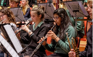 Students in a youth orchestra performing with oboes and flutes during a performance of Romany Wood