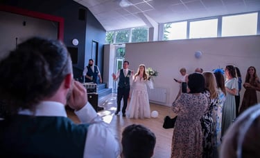 A bride and groom making their entrance at their wedding reception with guests watching.