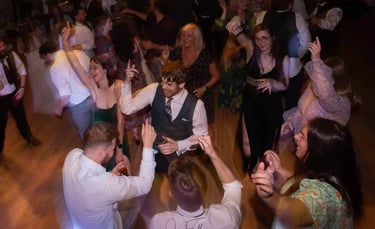 Wedding guests dancing and celebrating on a crowded dance floor during a lively reception party.