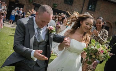 Newly-weds running through confetti