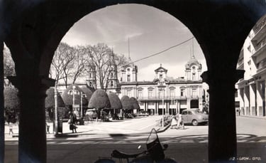 Vintage view of Leon, Guanajuato, Mexico, featuring historic architecture and park through an archway.
