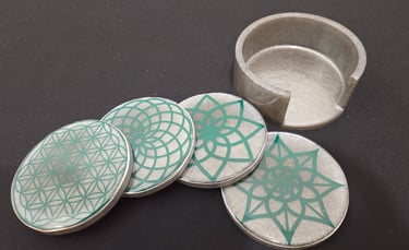 Set of four grey round coasters with green geometric mandala patterns and matching holder.