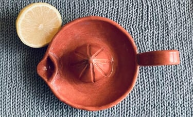 A handmade ceramic lemon juicer on a knitted background