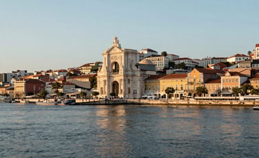 A professional wide-angle photograph of the Lisbon riverside at sunset, showing the Praça do Comércio area. The lighting is warm and clear, emphasizing a welcoming atmosphere. High-end architectural photography in European Portuguese style, with tones of light blue and pale blue.