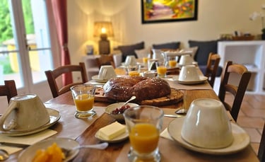 la ramade, table de la salle à manger dressée du petit-déjeuner, grosse brioche, confiture et jus .