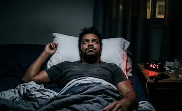 A man lying awake in bed at 3:07 AM, struggling with insomnia and sleep deprivation.