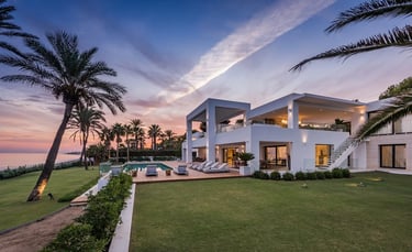 Contemporary beachfront villa at sunset with infinity pool and palm lined gardens