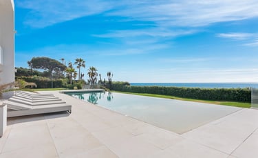 Outdoor infinity pool with sun loungers and open sea horizon