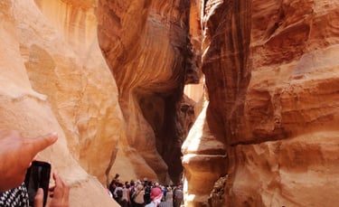 Grupo de turistas descendo pelo Siq em Petra, com as imponentes paredes rochosas à medida que o cami