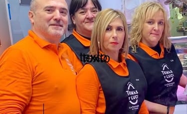 Empleados con protectores faciales y delantales en el mostrador de la carnicería Tomas y Luci.