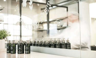 The Alche’Mist Serum Spray bottle beside green micro-algae and water droplets