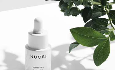Minimalist NUORI skincare bottles arranged on a white marble surface