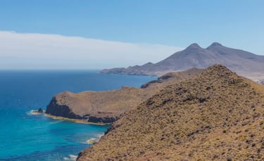 Panoramic coastal view of volcanic cliffs and turquoise water at Cabo de Gata-Níjar Natural Park in Spain.