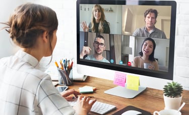 a woman sitting at a computer screen with a video chat