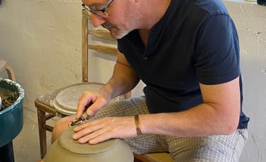 a man is making a clay potted potted with a wheel