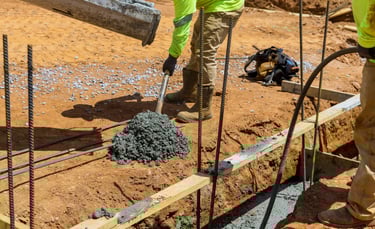 a man in a yellow jacket is pouring concrete into a concrete slab