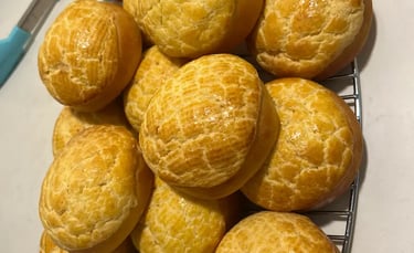 菠蘿包製成品「數個圓形金黃色 菠蘿包排放於烘焙紙盤上，表面紋理清晰、烘焙均勻，展現課堂麵包製作成果與質感細節。