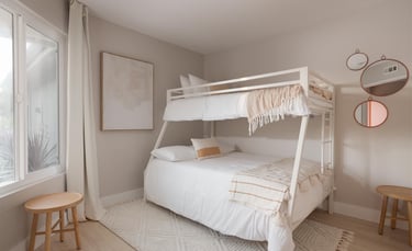 a white bunk bed in a beige room with a window