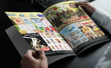 a person holding a magazine in front of a laptop