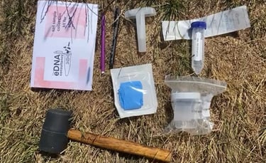 eDNA water filtration kit components including tubes, filters, syringes, parafilm, and a caulking gun, laid out on grass for