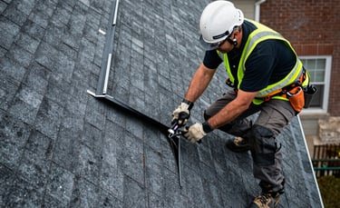 A detailed high-angle photograph of a roofing specialist in safety gear performing a precision leak inspection on an asphalt shingle roof of a North American / NYC residence. The scene uses charcoal black and steel gray tones, highlighting structural integrity and professional safety equipment.