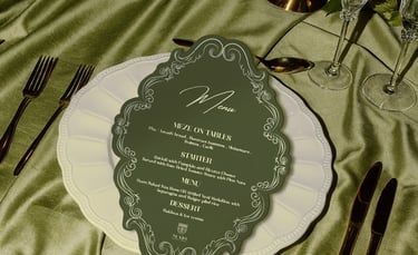 Elegant wedding table setting with a sage green menu card on a white scalloped plate and silk linens.