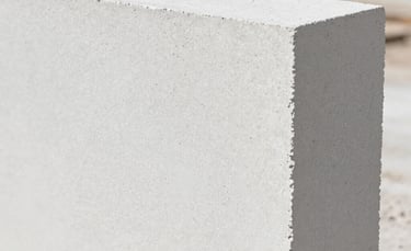 A close-up photograph of a clean, white Autoclaved Aerated Concrete block showing its fine porous texture. The lighting is bright and natural, reflecting a professional and sustainable construction setting in Western Mexico. Minimalist composition with a soft-focus background of a construction site.