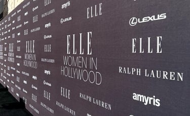 a woman in a black dress standing in front of a wall with a large sign