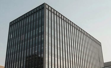 A professional and modern office building exterior in North American / US, featuring a sleek glass facade and clean lines. The shot is wide-angle with a soft light gray and slate gray color palette, under a clear sky, exuding a minimalist and approachable corporate vibe.