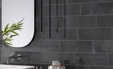 Modern bathroom with dark subway tile walls, featuring a sleek oval mirror, minimalist faucet.