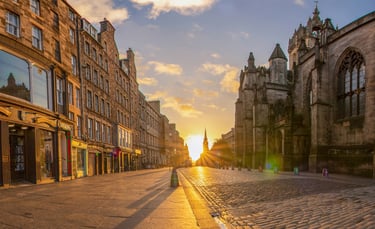 Royal Mile Edinburgh at sunrise with St Giles Cathedral and golden sunlight on empty cobblestones