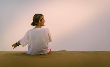 a woman sitting on a sand dune in the desert
