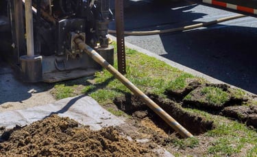 boring rig inserting a rod into the ground through a bore pit