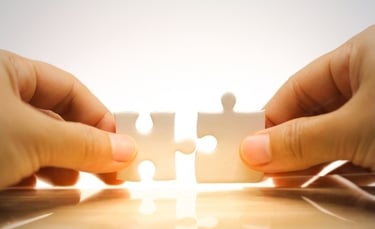 Deux mains assemblant des pièces de puzzle blanches sur fond lumineux