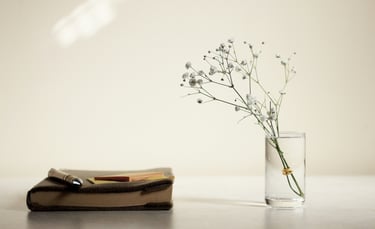 A vase, flowers and a book on a table 