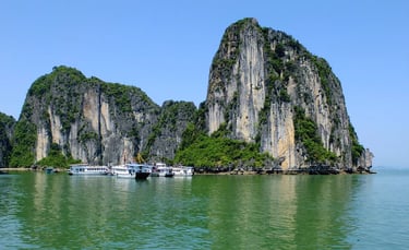 Tourist cruise boats anchored by limestone karst mountains in Ha Long Bay, Vietnam.