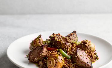 A premium, close-up shot of a gourmet halal dish on a minimalist white ceramic plate. The lighting is soft and natural, emphasizing textures and fresh ingredients. The background is a clean, light gray surface with plenty of white space. No people are visible.