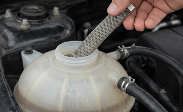 Adding a FuelMarble to a vehicle coolant tank, representing a legitimate fuel-saving technology