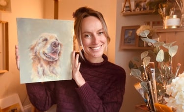 A photograph of Alex with one of her paintings