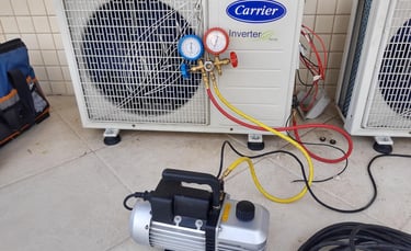 Vacuum pump and manifold gauges connected to a Carrier inverter AC unit for HVAC maintenance and repair.