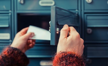 a person holding a piece of mail in front of a lockable post box