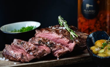 Geschnittenes medium-rare Ribeye-Steak mit Meersalz und Rosmarin auf Holzbrett.