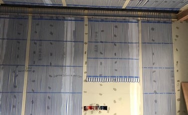 Blue capillary tube mats installed on a wall for an energy-efficient hydronic radiant heating and cooling system.