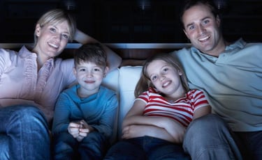 a family sitting on a couch watching tv