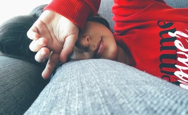 a woman is laying on a couch with her hands on her head
