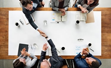 a group of business people shaking hands over a table