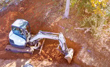 mini-excavator-digging-out-hillside.png