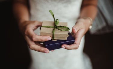 Bride holding small gift boxes—wedding gift idea for video package
