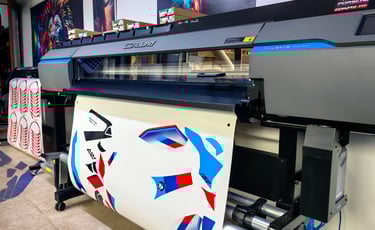 Roland TrueVIS wide format inkjet printer printing custom vinyl vehicle decals in a professional print shop.